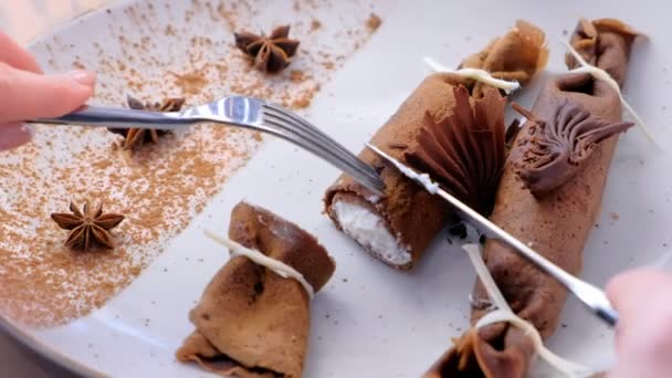 Donna, sta mangiando pancake russi al cioccolato, blini con ripieno di cagliata sul piatto. Mani in alto. Servito con tè. Mani in primo piano, vista laterale . — Video Stock