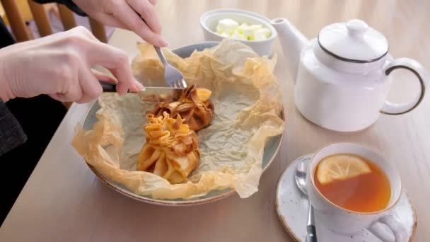 La femme mange de la julienne cuite au four dans une pâte servie sur une assiette de papier boulanger avec du thé et du beurre. Gros plan des mains . — Video