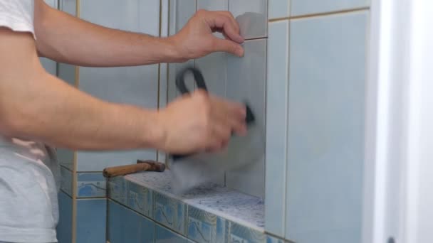Muž tiler dělat renovaci opravy doma, odstraňuje dlaždice ze zdi v WC. — Stock video