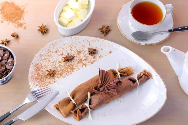 Panquecas russas de chocolate, blini com recheio de coalhada no prato. Servido com uma xícara de chá e manteiga . — Fotografia de Stock