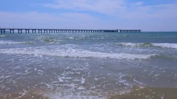 Große lange Seebrücke mit Straßenlaternenzaun und Hubschrauberplattform am Sandstrand. — Stockvideo