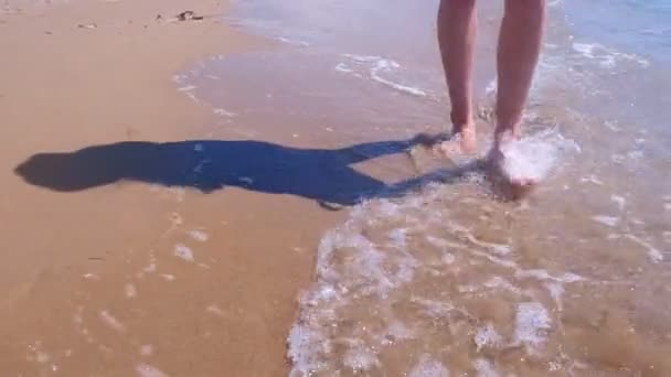 Descalza mujer turista camina en el agua en las olas del mar playa de arena, las piernas de cerca . — Vídeo de stock