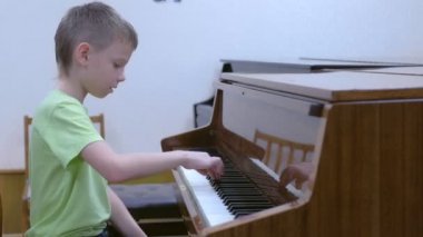 Çocuk okulda müzik dersinde piyano çalma alıştırması yapıyor..