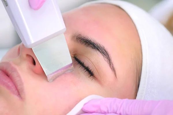 Косметолог проводит ультразвуковую процедуру очистки лица молодой женщине в клинике . — стоковое фото