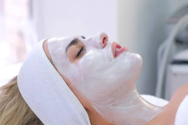 Retrato de mujer acostada en el salón de spa con máscara blanca en la cara, vista lateral . — Foto de Stock