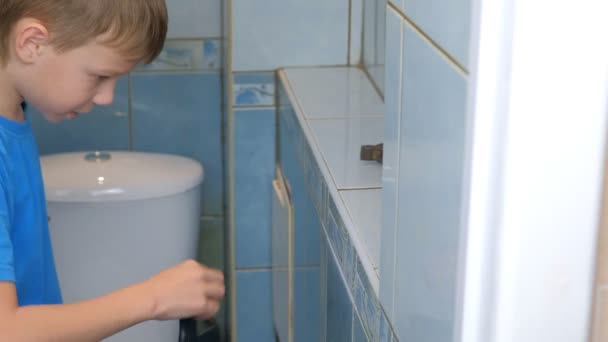Junge macht Renovierungsarbeiten zu Hause, er entfernt Fliesen von Wand in Toilette. — Stockvideo