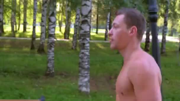 Junger Sportler joggt im Stadtpark mit nacktem Oberkörper, Seitenansicht. — Stockvideo