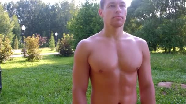 Portrait muscular young sportsman with naked torso in city park after training. — ストック動画
