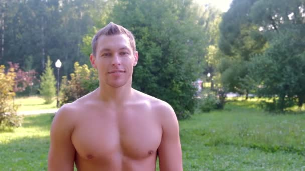 Retrato muscular sonriente deportista con torso desnudo en el parque de la ciudad, vista frontal . — Vídeos de Stock