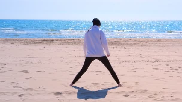 Mujer principiante trata de hacer triángulo yoga pose y cae sobre la arena en la playa del mar . — Vídeos de Stock