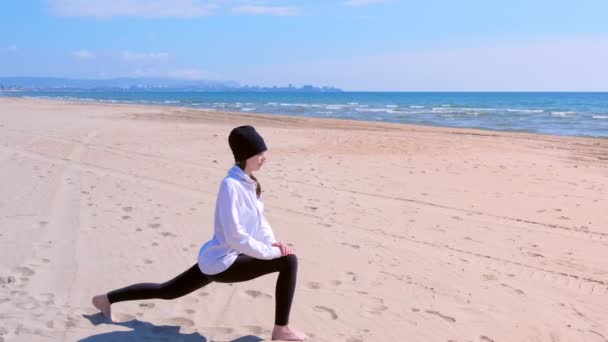 Vrouw doet hoge lunch pose op zee zandstrand Yoga Training sportoefening. — Stockvideo