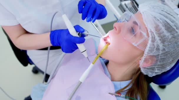 Mujer paciente en procedimiento de limpieza de dientes ultrasónicos en odontología, vista lateral . — Vídeo de stock