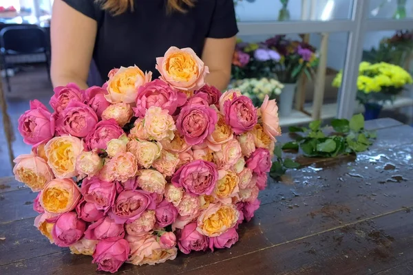 Kwiaciarnia robi bukiet różowych i pomarańczowych piwonii w kwiaciarni, zbliżenie. — Zdjęcie stockowe