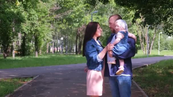 Retrato familiar en el parque de la ciudad con mamá, papá e hija bebé mirando a la cámara . — Vídeos de Stock