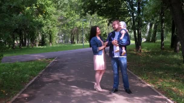 Family portrait in city park with mom, dad and baby daughter oh dads hands. — Stock Video
