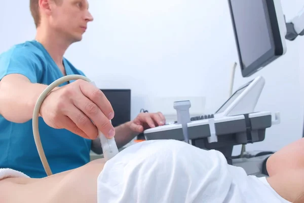 Мужчина врач делает УЗИ брюшной полости для диагностики желудка женщине в клинике . — стоковое фото