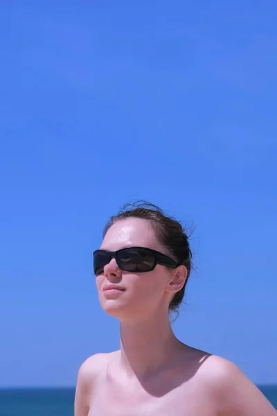 Портрет женщины загорания стоять на пляже солнцезащитные очки на море и небо фоне . — стоковое фото