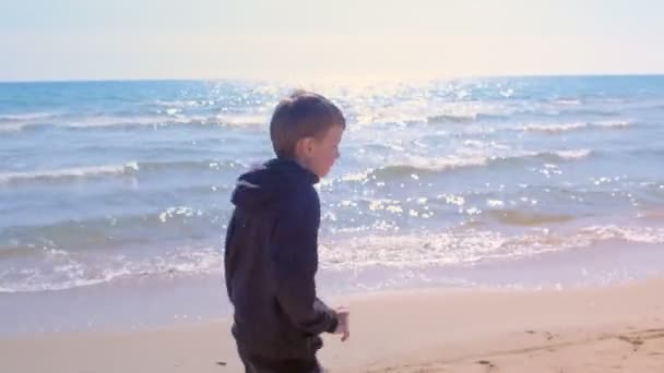 Niño niño está corriendo en la playa de arena de mar pequeño corredor deporte al aire libre vista lateral . — Vídeo de stock
