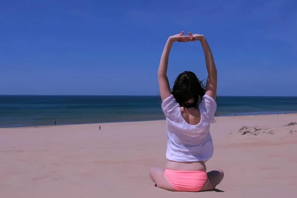 Mujer estiramiento yoga práctica se sienta loto pose arena mar playa manos arriba espalda vista . — Foto de Stock