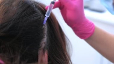 Doktor trikoloğum kadının kafa derisine mezoterapi yapıyor..