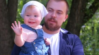 Kızını kucağında tutan genç bir baba şehir parkında yürüyor, aile fotoğrafı..