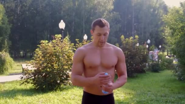 Sportman van naakte romp drinkwater uit fles in stadspark na training. — Stockvideo