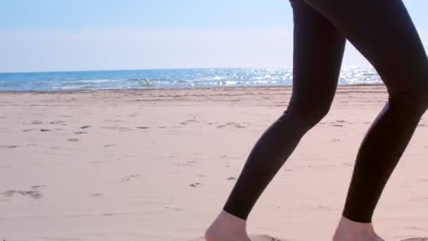 Descalzo niñas piernas en leggings es trotar en mar arena playa deporte correr . — Vídeo de stock