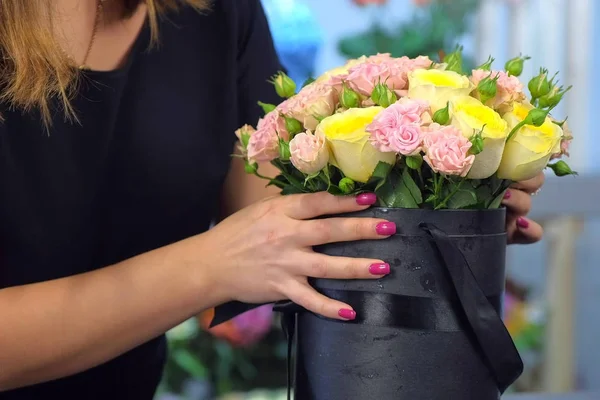 Kwiaciarnia kobieta robi bukiet róż w opakowaniu czarna skrzynka w sklepie, zbliżenie. — Zdjęcie stockowe