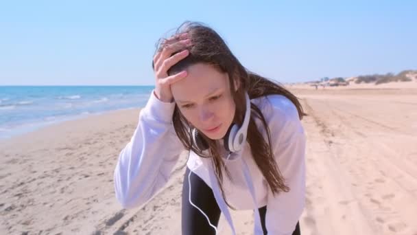 Dziewczyna zatrzymać jogging złapać oddech sport biegać trening morze piasek plaża słuchawki. — Wideo stockowe