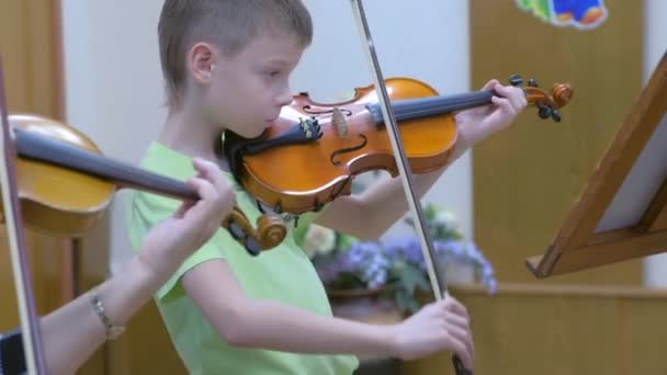 Мальчик-ребенок играет на скрипке с учителем на уроке музыки в музыкальной школе . — стоковое видео