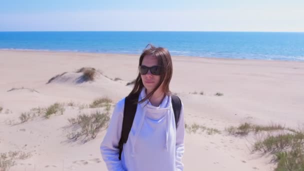 Tatilde deniz kumu sahilde sırt çantası ile genç kadın gezgin portresi. — Stok video