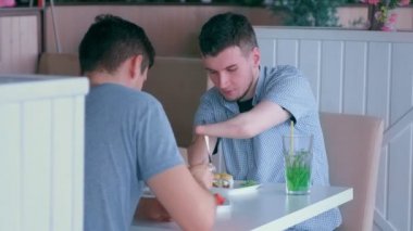 İki tane kütüğü olan engelli adam arkadaşıyla buluşup kafede konuşuyor.