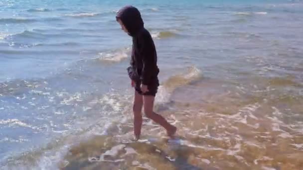 Niño descalzo camina en la playa de arena en el agua de mar de vacaciones . — Vídeos de Stock