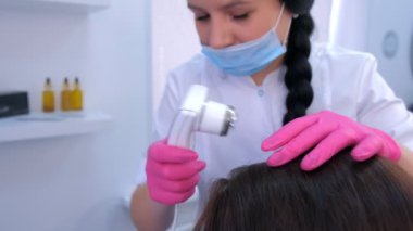 Trikoloğum klinikte bilgisayar trikoskopisi kullanarak kadın hasta kıllarını inceliyor..