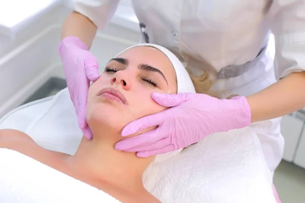 Cosmetologist in gloves washes clients woman face, neck and chest with gel. — Stock Photo, Image