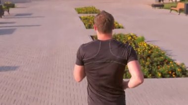 Genç sporcu yaz güneşli bir günde şehir parkında koşuyor..