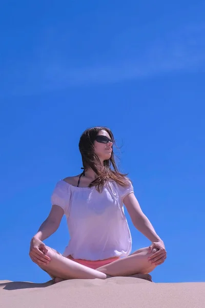 Mujer meditar se sienta playa de arena sobre fondo cielo azul yoga práctica pose . —  Fotos de Stock