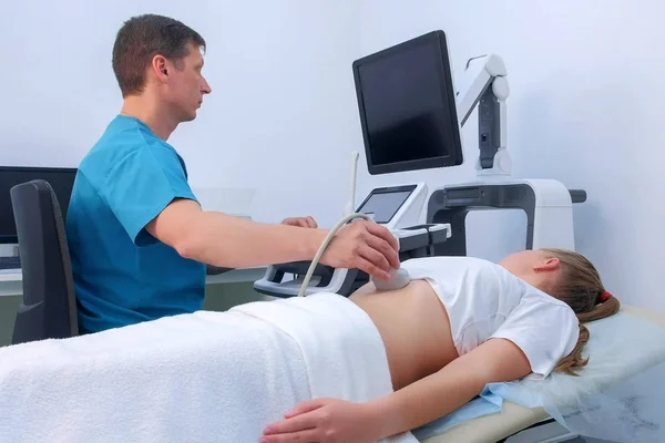 Man doctor making abdominal ultrasound to diagnostic stomach to woman in clinic. — Stock Photo, Image