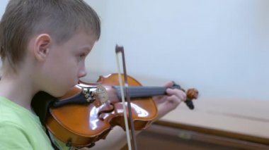 Çocuk okulda müzik dersinde keman çalma alıştırması yapıyor..