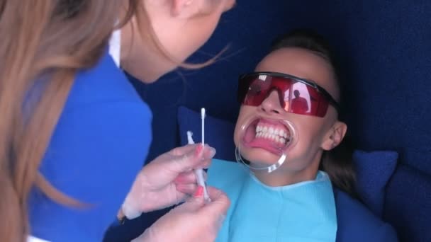 Infermiera che applica gel per lo sbiancamento a LED su pazienti donna denti in odontoiatria . — Video Stock