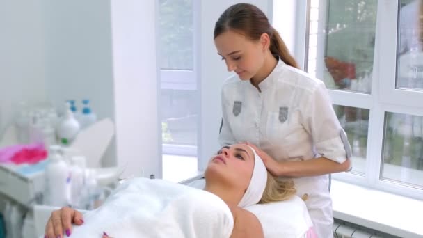 Cosmetoloog voorbereiding klant naar cosmetische schoonheid procedure zetten hoofdband. — Stockvideo