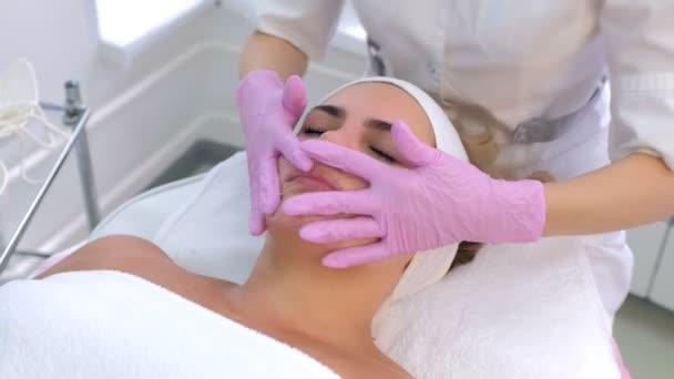 Cosmetologist in gloves washes clients woman face, neck and chest with gel. — Stock Video