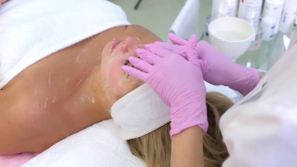 Cosmetologist in gloves washes clients woman face, neck and chest with gel. — Stock Video