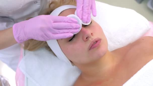 Cosmetologo in guanti pulisce clienti donna viso pulire con batuffoli di cotone . — Video Stock