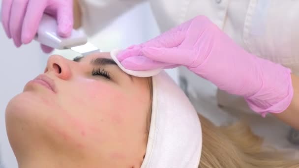 Cosmetologue fait une procédure de nettoyage du visage par ultrasons à la jeune femme en clinique . — Video