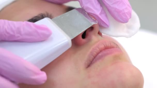 Косметолог проводит ультразвуковую процедуру очистки лица молодой женщине в клинике . — стоковое видео