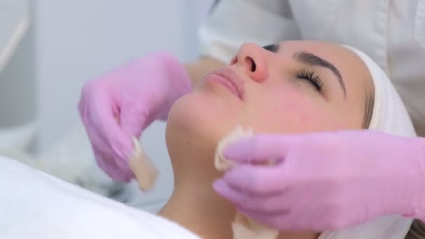 Cosmetologist in gloves wiping skin care mask from woman face, closeup portrait. — Stockvideo