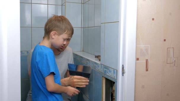 Papa et fils faire des rénovations ensemble à la maison, enlever les tuiles des murs dans les toilettes . — Video