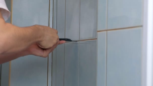 Άντρας tiler κάνει ανακαίνιση στο σπίτι, αφαιρεί πλακάκια από τον τοίχο στην τουαλέτα. — Αρχείο Βίντεο
