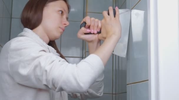 Γυναίκα tiler κάνει ανακαίνιση στο σπίτι, αφαιρεί πλακάκια από τον τοίχο στην τουαλέτα. — Αρχείο Βίντεο